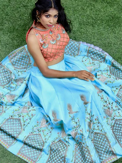 I love playing with contrasting colors and textures. This custom lehenga features a sky-blue skirt with bird and architectural embroidery, paired with a quilted peach crop top. It’s a unique combination for someone who wants to try something new.