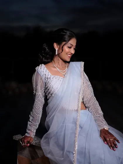 A smiling portrait of the bride. The makeup is soft and romantic, with a focus on luminous skin and gently defined eyes, perfect for her sangeet night.
