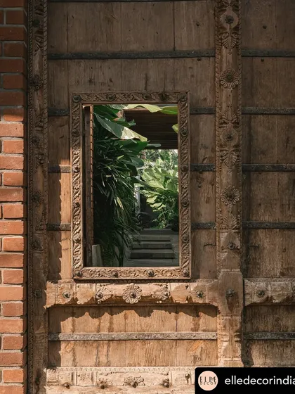 A reclaimed wooden door features a mirror that reflects the garden, cleverly bringing the landscape inside. This detail is part of a larger strategy to ensure every corner of the home has a connection to the green spaces I designed.