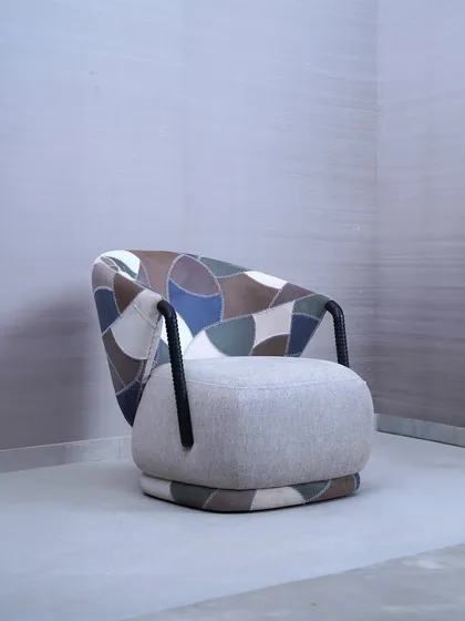 This accent chair is a testament to our love for materials, featuring a unique patchwork of leather and fabric in earthy tones. The design combines a plush, comfortable seat with a sculptural, curved back and textured armrests, making it a standout piece in any room.