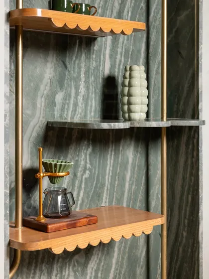 A detail of the custom shelving at 11 Grams Cafe. We mixed scalloped-edge wood shelves with green marble, all held within a delicate brass frame, creating a beautiful display for coffee-making tools and decor.