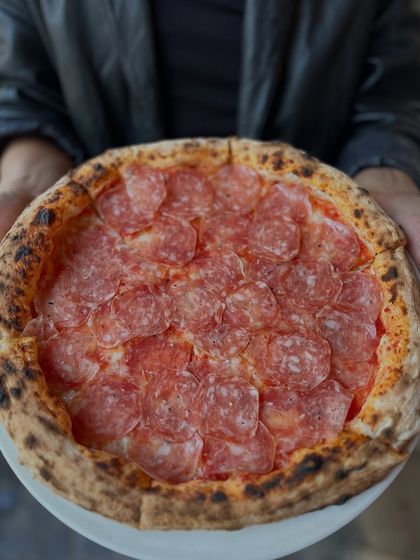 Holding up the truffle salami pizza. It's a beauty.