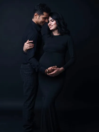 Timeless, classic, and elegant. A simple black dress against a dark backdrop puts all the focus on the couple's connection and the beautiful silhouette of the baby bump.
