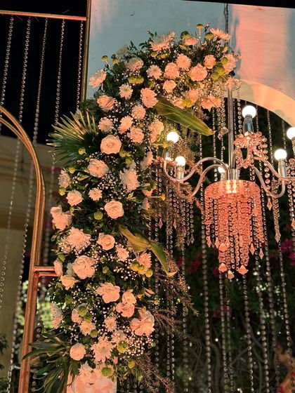 A close-up of a floral arch with a mini chandelier, a perfect example of how I combine lighting and flowers to create magical details.