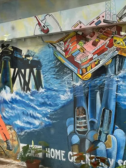 A wider view of the ONGC energy solutions mural, showing workers and equipment in a dramatic seascape.