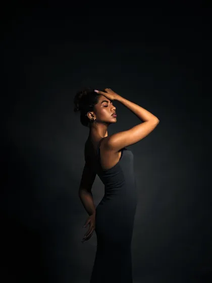 An elegant and emotional pose. The lighting highlights the graceful curve of her arm and the serene look on her face.