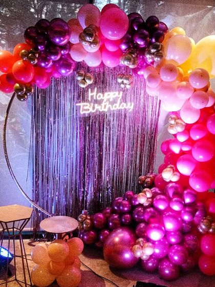 A vibrant and colorful balloon half-arch on a ring frame. The mix of pink, purple, and orange creates a festive and energetic vibe.