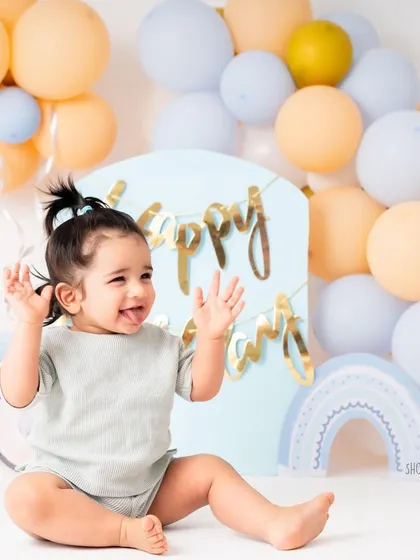 Another joyful moment from the same one year milestone session. The simple setup with pastel balloons keeps the mood light and celebratory, focusing on the baby's happiness.