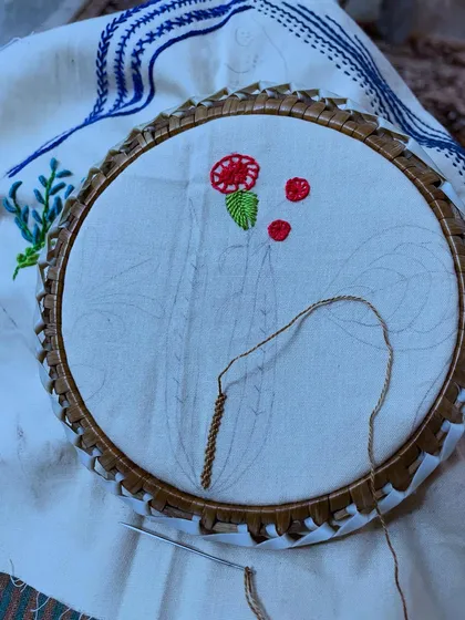 A close-up of the work-in-progress hoop art, showing the detail of the stitches. Each element is carefully considered to contribute to the overall design.