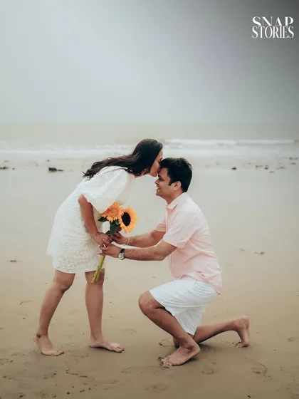 A sweet and tender moment as the groom-to-be kisses his fiancée's forehead during their pre-wedding photoshoot on the beach.