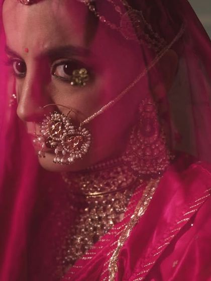 A close-up through the veil. Her defined eyes and traditional nath are the focus, with the makeup kept fresh and natural.