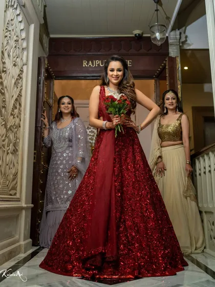 A confident bride in a stunning red gown, ready for her reception. Her pose and expression exude style.