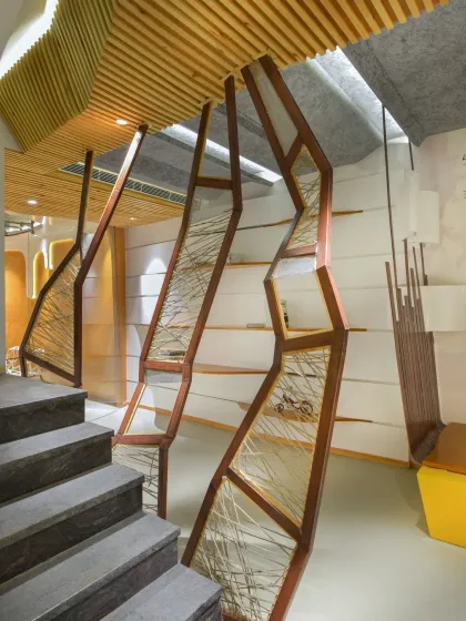 A detail of the staircase partition at the AMG office. The geometric wooden frame is filled with a mesh-like weave of threads, acting as both a screen and a structural element that adds texture and lightness to the space.