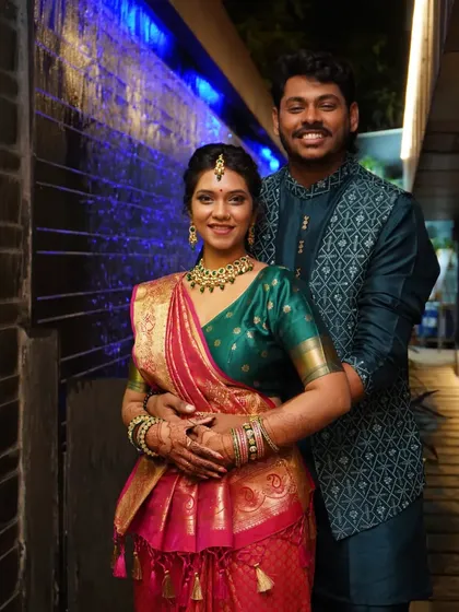 A classic portrait of the couple smiling for the camera, set against a modern, illuminated wall feature.