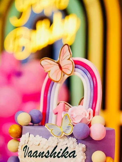 The birthday cake is a centerpiece of the celebration. We coordinate with bakers to ensure the cake, like this one for Vaanshika with rainbow and butterfly details, perfectly matches our decor.