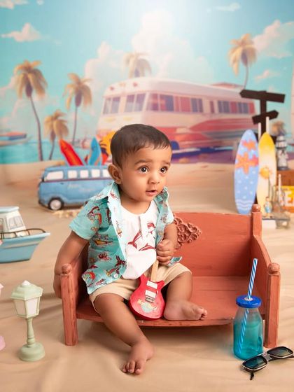 Life's a beach. This little rockstar is ready for some sun and sand in our fun, beach-themed studio setup, complete with a mini guitar, surfboards, and a retro van backdrop.