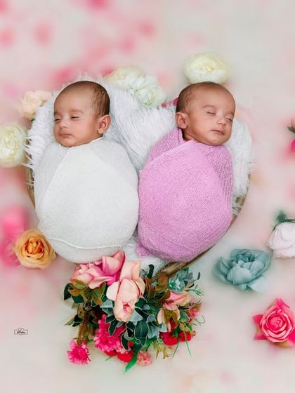 A beautiful overhead shot of newborn twins sleeping peacefully together. The floral arrangement and soft background add a touch of magic to this special memory.