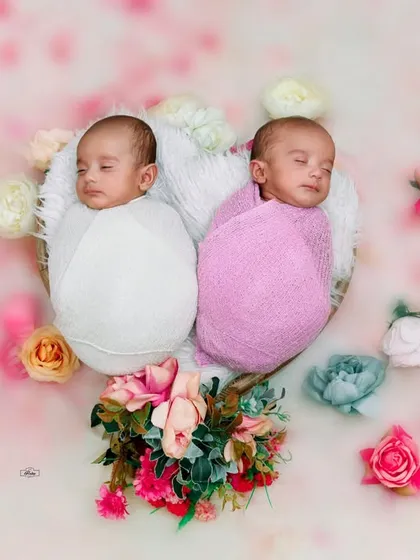 A beautiful overhead shot of newborn twins sleeping peacefully together. The floral arrangement and soft background add a touch of magic to this special memory.