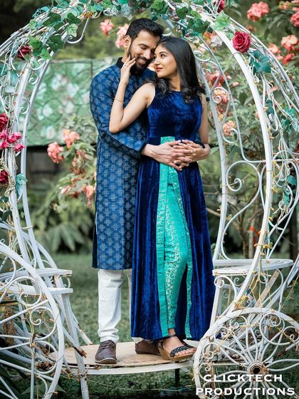 A fairy-tale-like photo of a couple posing in a white, carriage-shaped prop adorned with flowers.