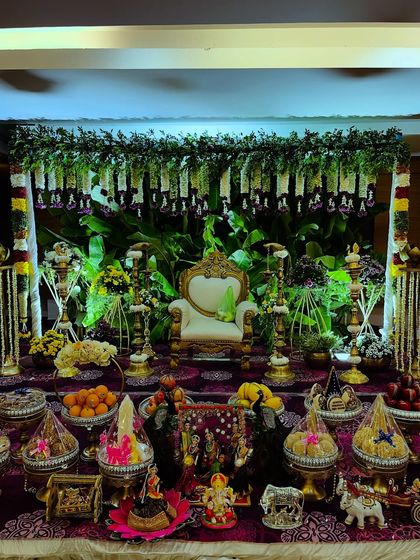A full view of a lush green Seemantham setup, complete with a banana leaf backdrop, hanging garlands, and an extensive display of traditional offerings. The lighting enhances the sacred feel of the ceremony.