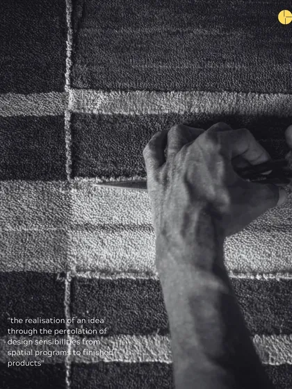 A black and white photo capturing the intense focus of a craftsman's hand at work on one of the Elemental rugs.