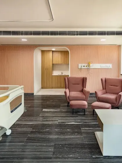 We design patient rooms to be havens of comfort and elegance. This private suite features a sophisticated color palette, comfortable seating for visitors, and soft lighting, transforming the clinical environment into a space that nurtures both body and mind.