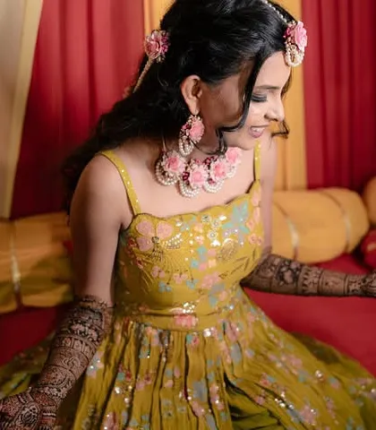 A happy Mehendi bride admiring her intricate henna design. Her makeup was kept fresh and natural to match the daytime event.