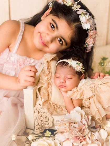 A close-up of a big sister's love. She rests her head near her sleeping newborn sibling, a quiet moment of pure affection.