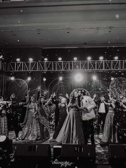 A black and white shot of the grand finale of a Sangeet performance, with confetti raining down on the entire group.