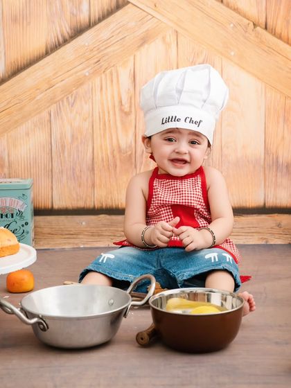 With a sweet, shy smile, this little chef is ready for his close-up in our rustic kitchen scene.