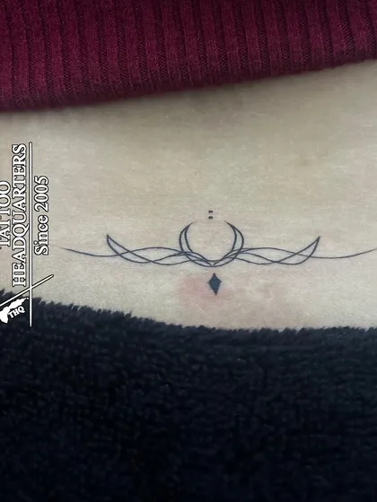 A delicate and symmetrical ornamental design for the lower back, a popular style of minimalist tattoo.