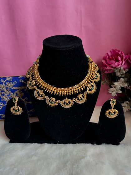 A full view of the two-layered golden bead necklace with green stones. It's a simple yet beautiful piece for any occasion.