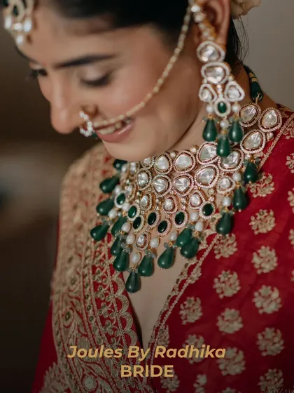The joy of a bride is in the details. A close-up of our bride's smile, framed by her exquisite emerald and polki necklace and matching nath, capturing the essence of her wedding day glow.