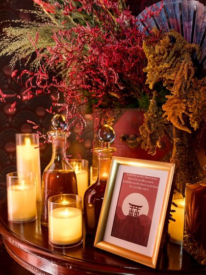 We use lighting and accessories to build atmosphere. Here, a collection of candles in glass holders and elegant decanters are grouped with a framed piece of thematic art, creating a warm and inviting glow.