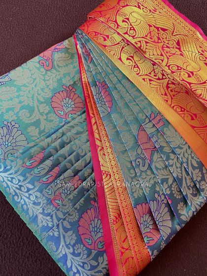 A stunning turquoise and pink silk saree, perfectly box-folded to showcase its vibrant colors and intricate design.