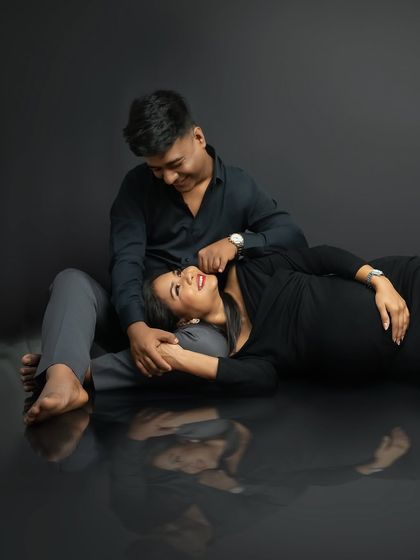 Lost in their own world. This intimate pose, with the mother-to-be lying in her partner's lap, creates a beautiful feeling of safety and connection. The reflection adds an artistic, dreamy quality.