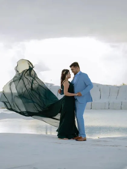 The dark green gown billows like a sail against the cloudy sky, creating a dramatic and powerful image. This is a shot that truly makes a statement.