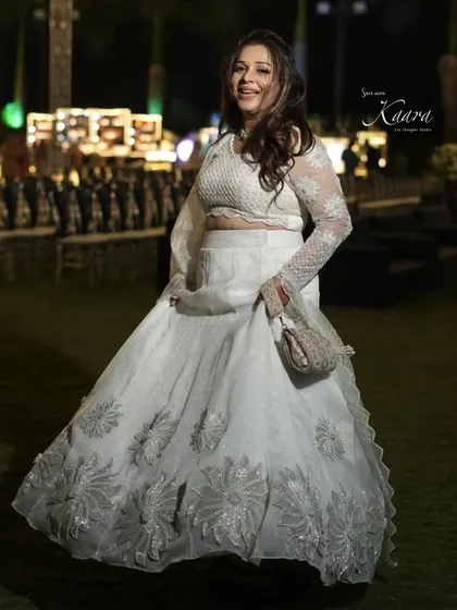 Twirling with joy. Our client in her custom white lehenga, featuring silver floral appliqué on the skirt and delicate embroidery on the sheer sleeves.