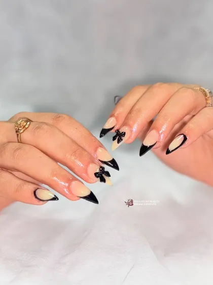The full set of black-tipped stiletto nails with sculpted bows. The combination of the sharp tip and the soft bow creates a beautiful contrast.