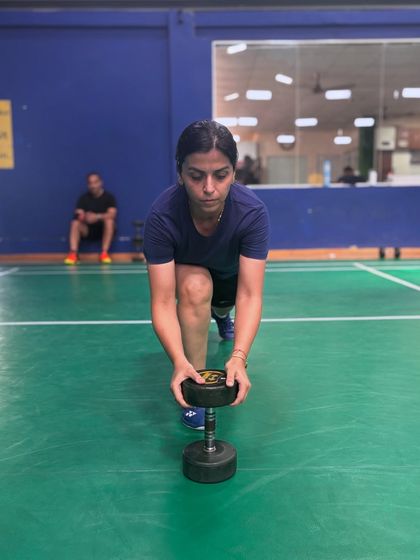 A player demonstrates focus and form while performing a weighted lunge. This exercise is perfect for building the single-leg strength required for deep lunges on the court.