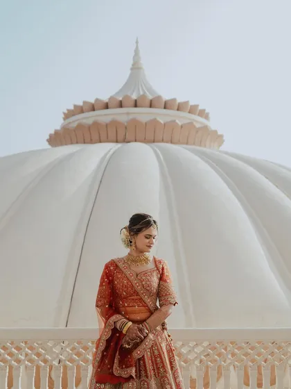 A stunning bridal portrait against the grand white dome of Indana Palace. The architectural symmetry and the bride's elegant pose create a powerful and regal image.
