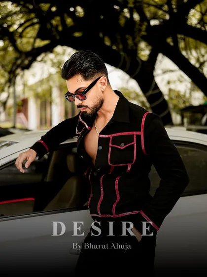 Confidence tailored to perfection. This shot shows the black and red piped jacket in a relaxed pose, leaning against a car.