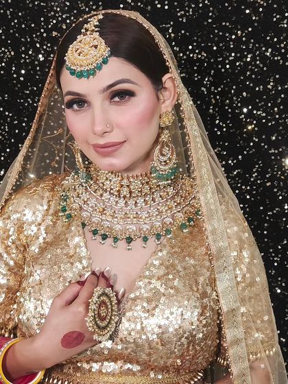 A bride in a golden sequin lehenga wearing a Pachi Kundan set with green beads. The sparkling background makes the jewellery pop.