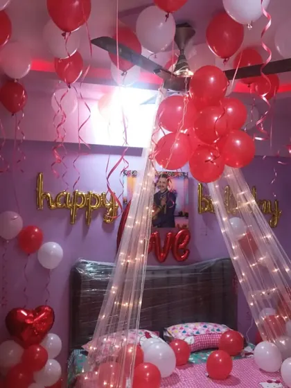 The romantic canopy setup under brighter light, showing the "Happy Birthday" banner and photo on the wall.