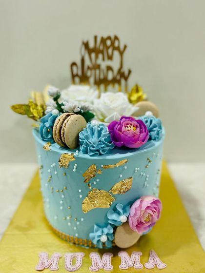 A full view of the elegant blue cake with macarons and flowers.