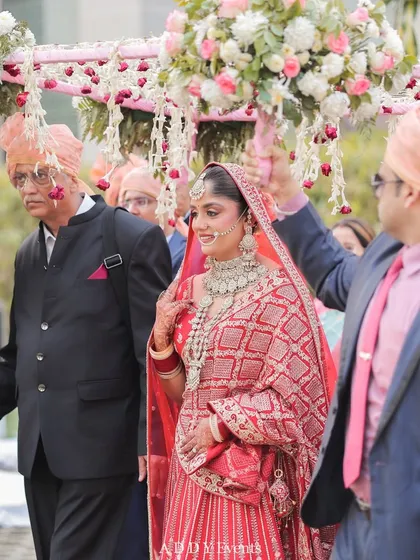The bride's grand entrance, walking gracefully under a beautiful floral chaadar held by her brothers and father.