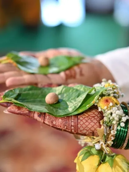A shot capturing a traditional wedding ritual, with the bride's mehendi-adorned hand holding a betel leaf.