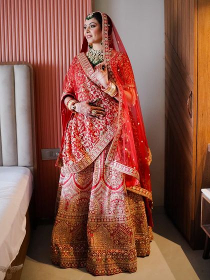 The bride stands gracefully in her room, fully ready. The draping of her dupatta and the finish of her makeup are impeccable.