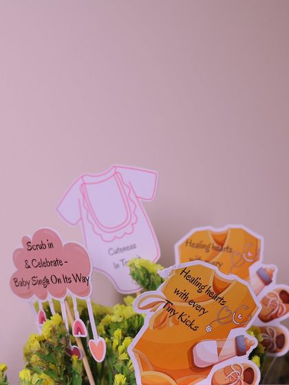 A closer look at the personalized decorative picks, featuring adorable baby-themed graphics and clever phrases that tie into the parents' profession.
