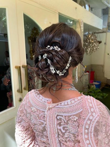 A detailed shot of a romantic, messy updo. I wove a delicate, leafy silver accessory through the bun to match the client's diamond jewelry.
